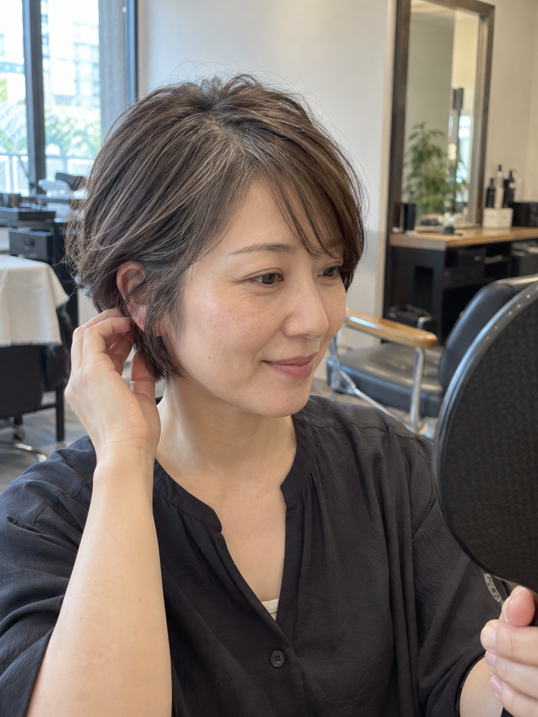 前髪と顔周りの白髪ぼかしを鏡で確認する40代女性