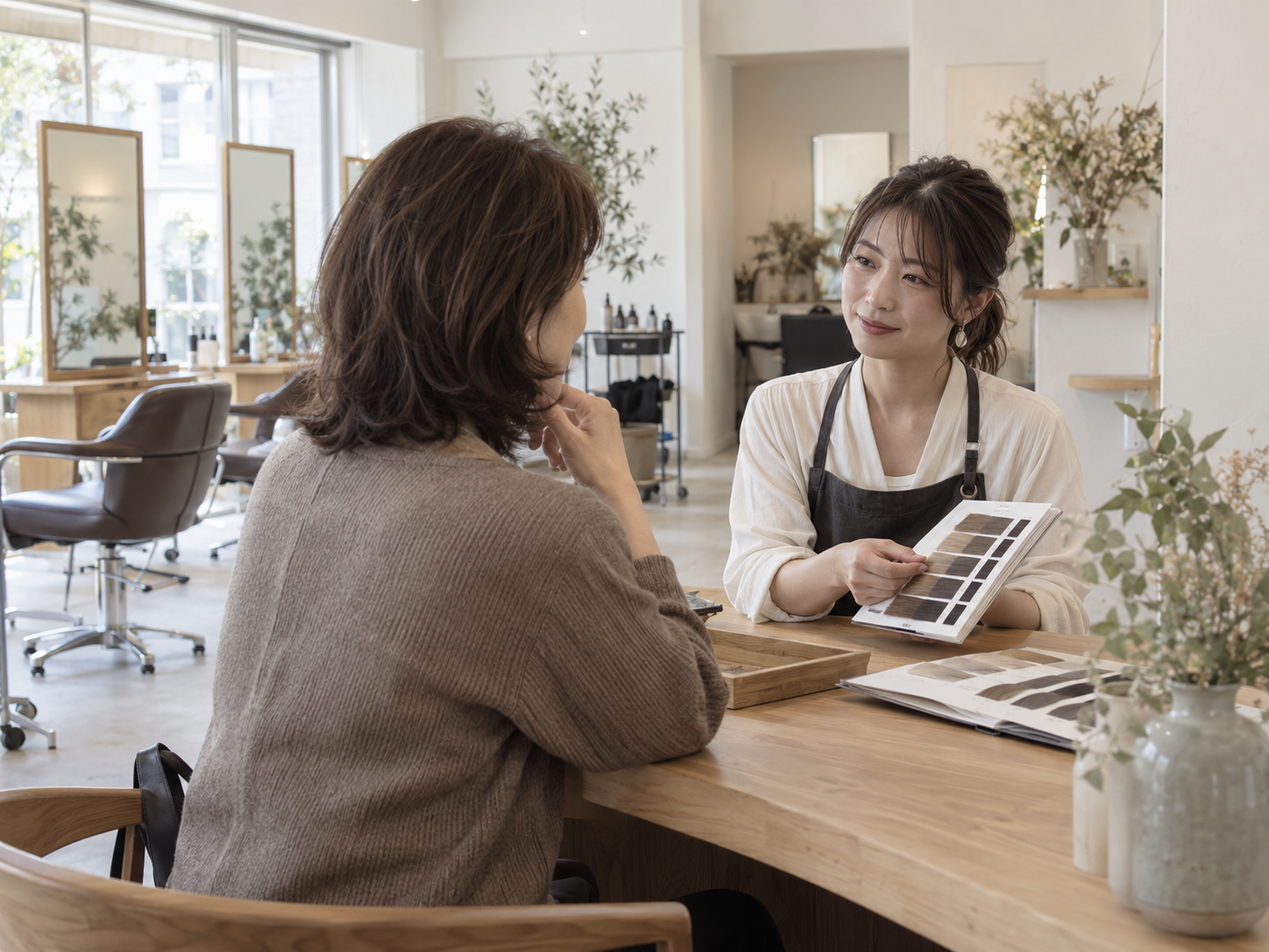 美容師と色見本を見ながら白髪ぼかしを相談する女性