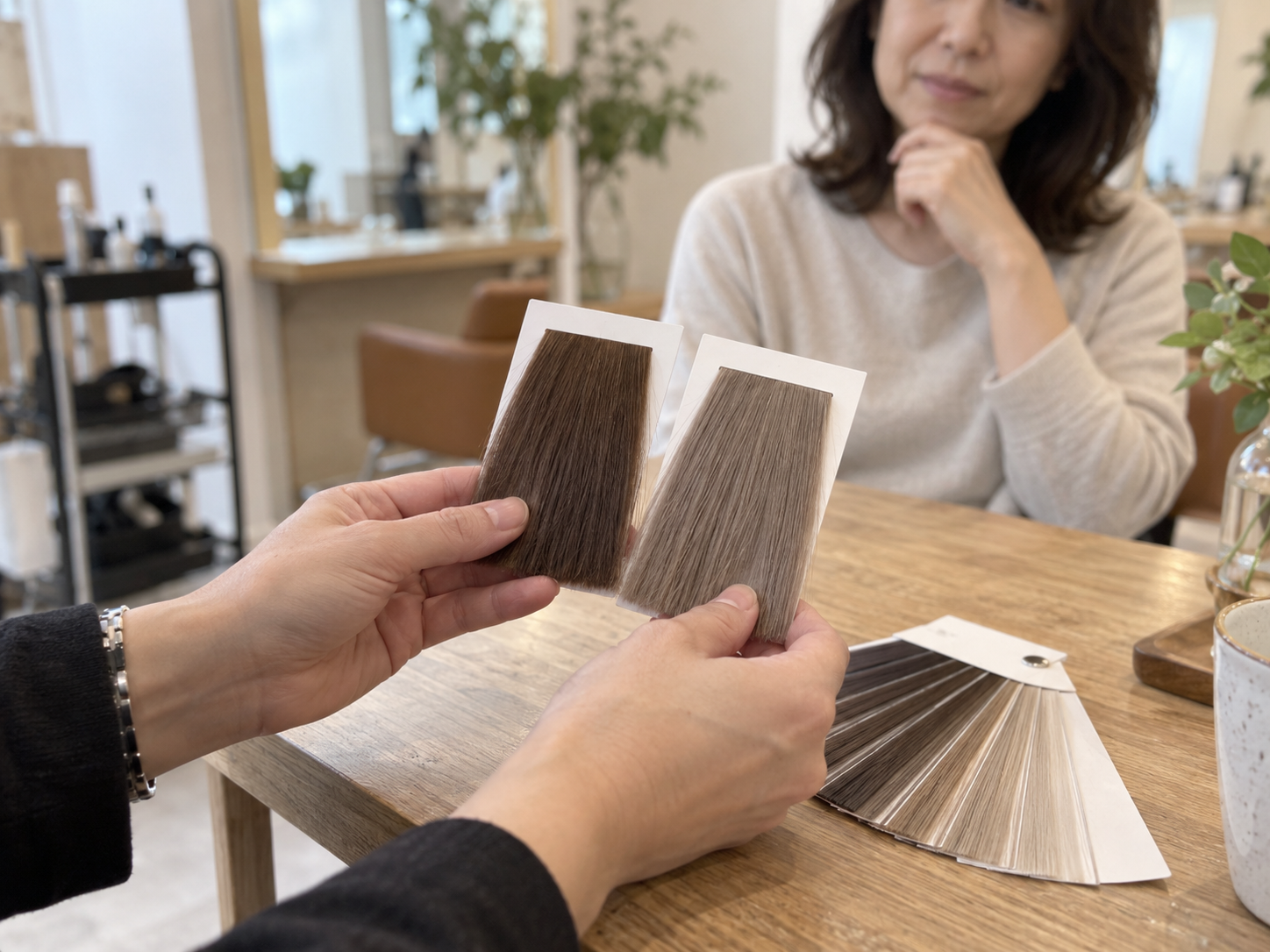 美容師と髪色の毛束を見比べて相談するイメージ